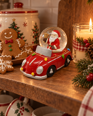 Schneekugel Auto rot auf einem Küchenregal mit Lebkuchen und Kerze
