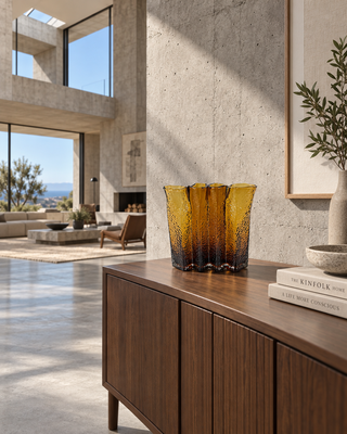 Glasvase Bernstein gewellt auf einem Sideboard aus Holz im hellen Wohnraum