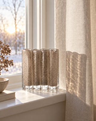 Glasvase Taupe gewellt auf der Fensterbank mit Leinenvorhang