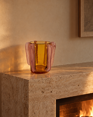 Glasvase Orange mit rosa Henkeln auf einem Kaminsims aus Travertin