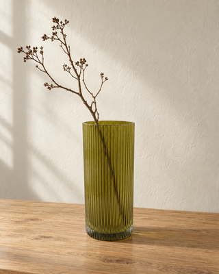 Glasvase Grün gerillt mit Zweig auf einem Holztisch