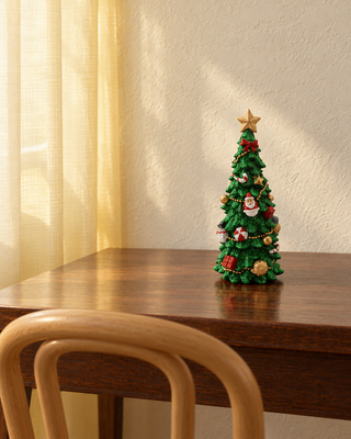 Deko-Weihnachtsbaum Grün auf einem Holztisch am Fenster