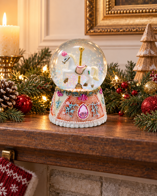 Spieluhr Schneekugel Pferd rosa auf einem Kaminsims mit Tannengirlande