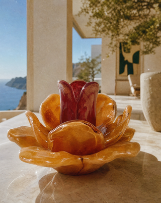 Kerzenhalter aus Glas in Peach, florale Form für Teelichter, auf einem Tisch im hellen Wohnzimmer mit Meerblick