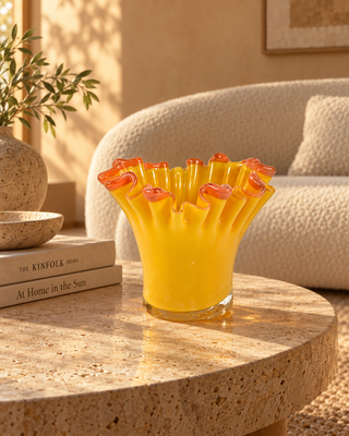 Glasvase Orange mit Rüschenrand auf einem runden Couchtisch aus Travertin